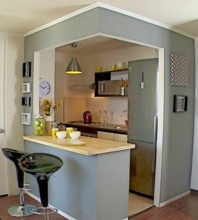 a kitchen with an island and bar stools in the middle, next to a refrigerator