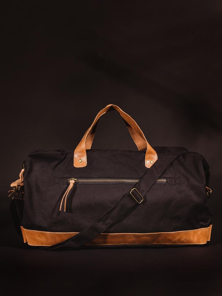 Black colored handcrafted canvas duffle bag with leather straps on black studio background. Canvas Weekender Bag, Canvas Satchel, Trip To Paris, Weekend Bag, Long Trips, Phone Pouch, Long Weekend, Tan Color, Vegetable Tanned Leather