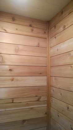 an empty sauna with wood paneling in the corner and light coming from above