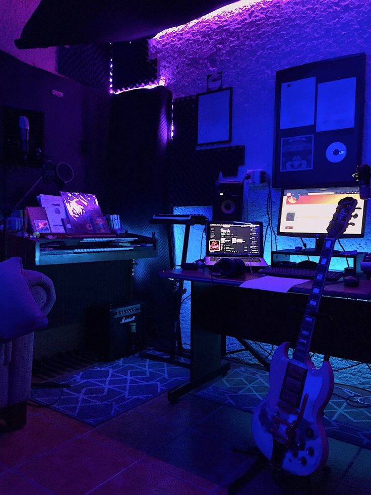 a room filled with musical equipment and purple lighting on the walls, along with a guitar