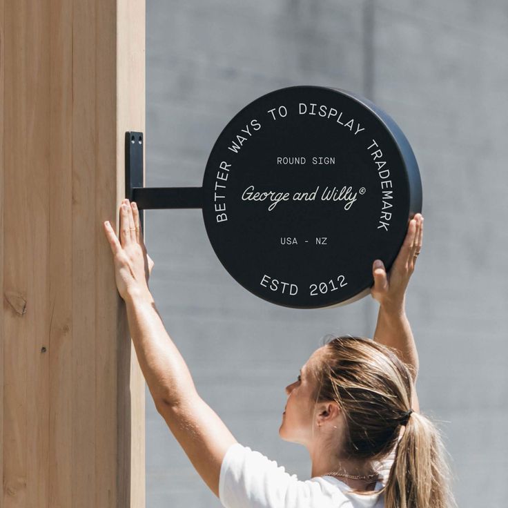 a woman is holding up a plaque on the side of a building