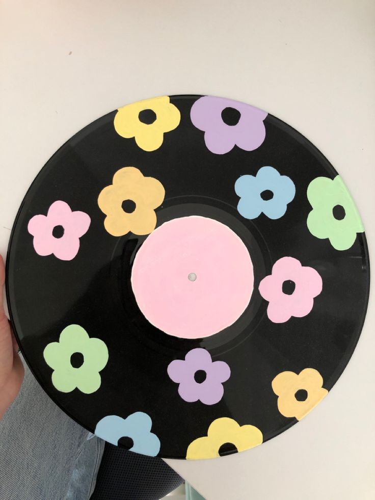 a person holding up a record with flowers painted on it