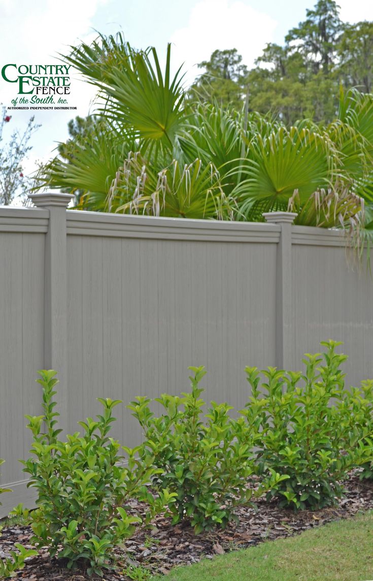 a fenced in area with green plants and bushes next to the fence is shown