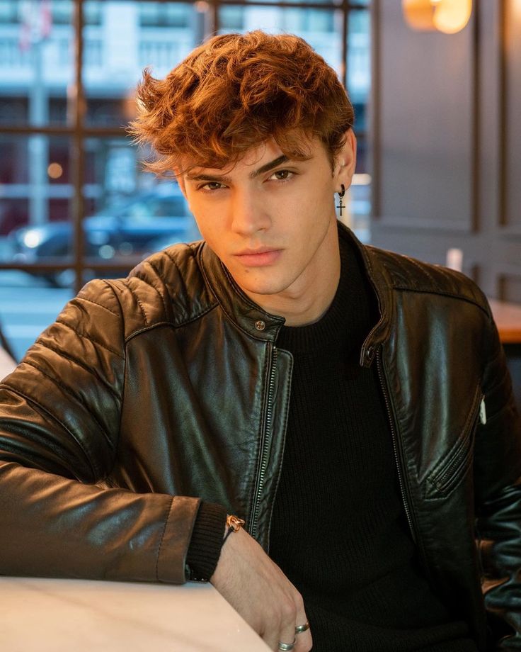 a young man sitting at a table with his hand on his hip and looking off to the side