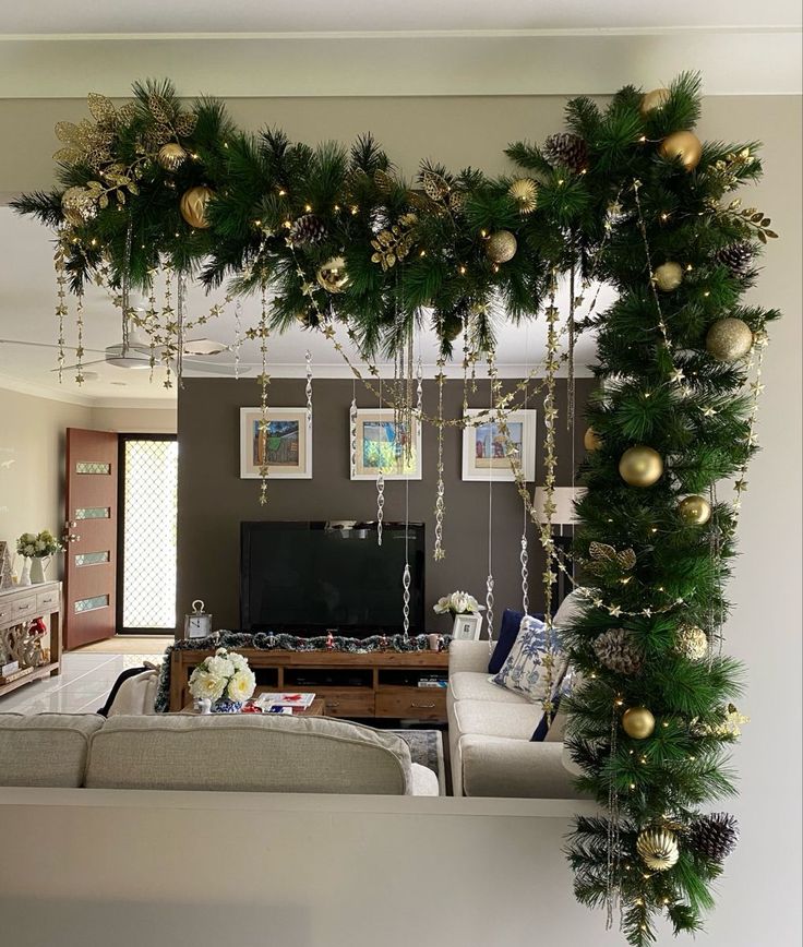 a living room decorated for christmas with garlands and ornaments hanging from the ceiling above