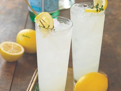 two glasses filled with lemonade sitting on top of a table next to some lemons