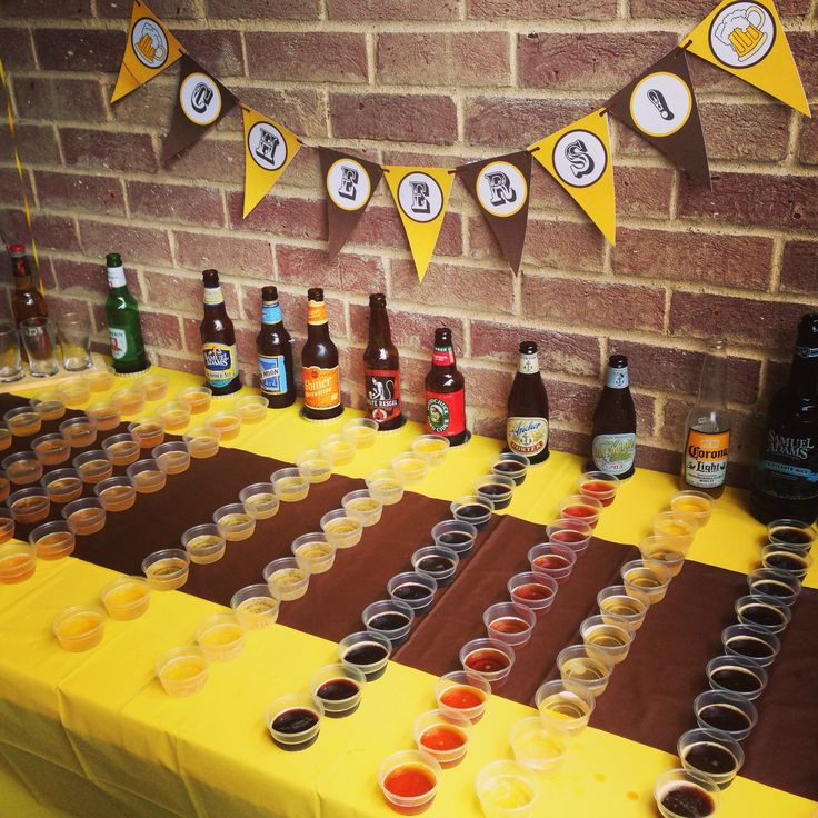 a table topped with lots of cups filled with drinks next to bottles and paper bunting