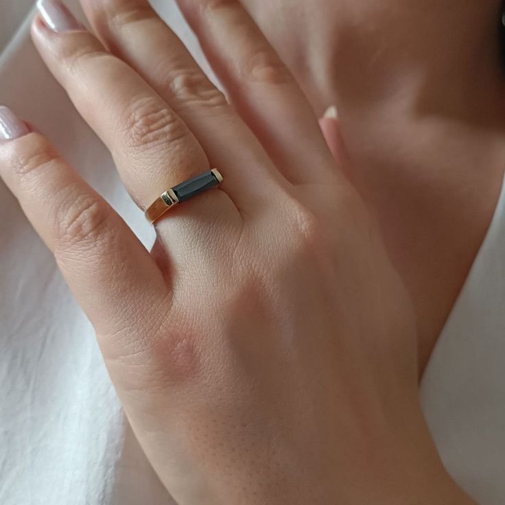 a woman's hand wearing a gold ring with a blue stone on it,