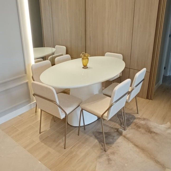 a white table with four chairs and a vase on it in the middle of a room