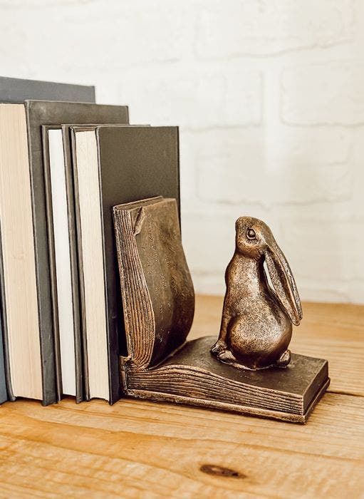 a bookend with a rabbit figurine sitting on top of it next to two books