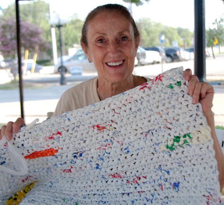 an older woman holding up a crocheted blanket with colorful sprinkles