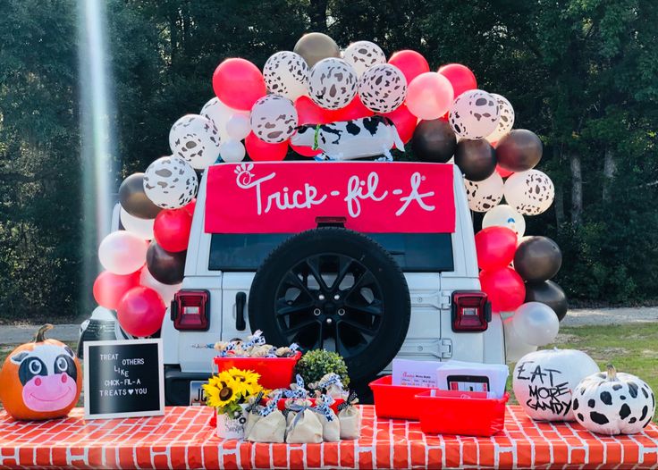 a decorated truck with balloons and decorations on the back sits in front of a picnic table