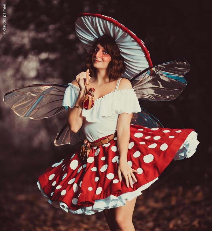 a woman dressed up as a fairy with wings and a polka dot dress holding an umbrella