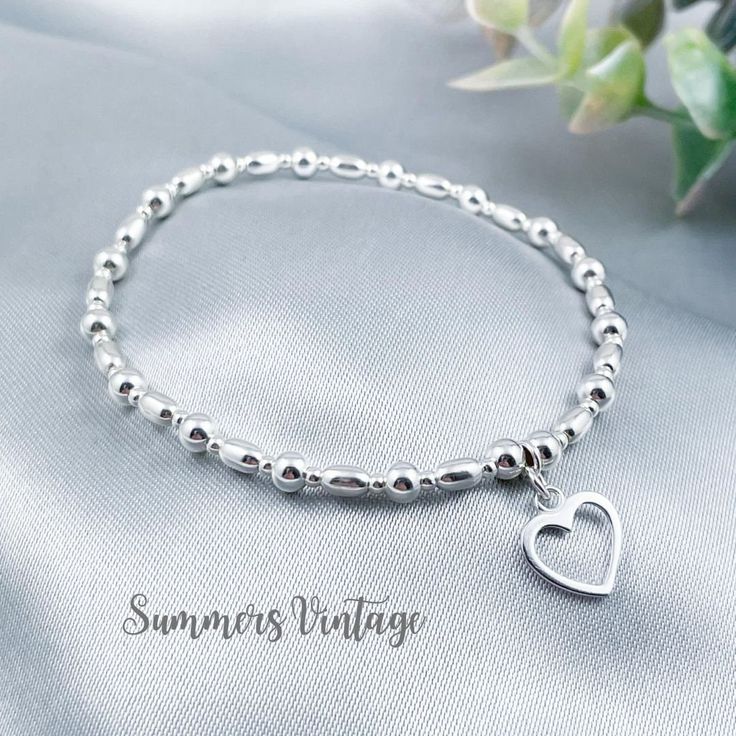 This simple and dainty sterling silver bracelet featuring a beautiful open-heart charm looks stunning worn alone or stacked alongside other bracelets for a Bohemian feel   The eclectic mix of beautiful beads are strung on high quality, strong, professional jewellers' elastic meaning there are no fiddly clasps to deal with, the bracelet can simply be rolled over the hand and onto the wrist The bracelet is elegantly presented in a beautiful jewellery pouch, complete with aftercare instructions and Dainty Jewelry With Heart Charm And Round Beads, Silver Metal Beaded Bracelets Dainty Style, Silver Metal Dainty Beaded Bracelets, Elegant Silver Beaded Bracelets With Heart Charm, Dainty Silver Metal Beaded Bracelets, Elegant Silver Beaded Bracelet With Heart Charm, Everyday Jewelry With Heart Charm And Round Beads, Elegant Charm Bracelet With Heart And Round Beads, Elegant Sterling Silver Beaded Bracelet With Heart Charm