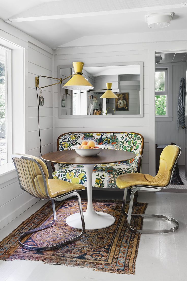 the interior of a living room with yellow chairs and a round table in front of it