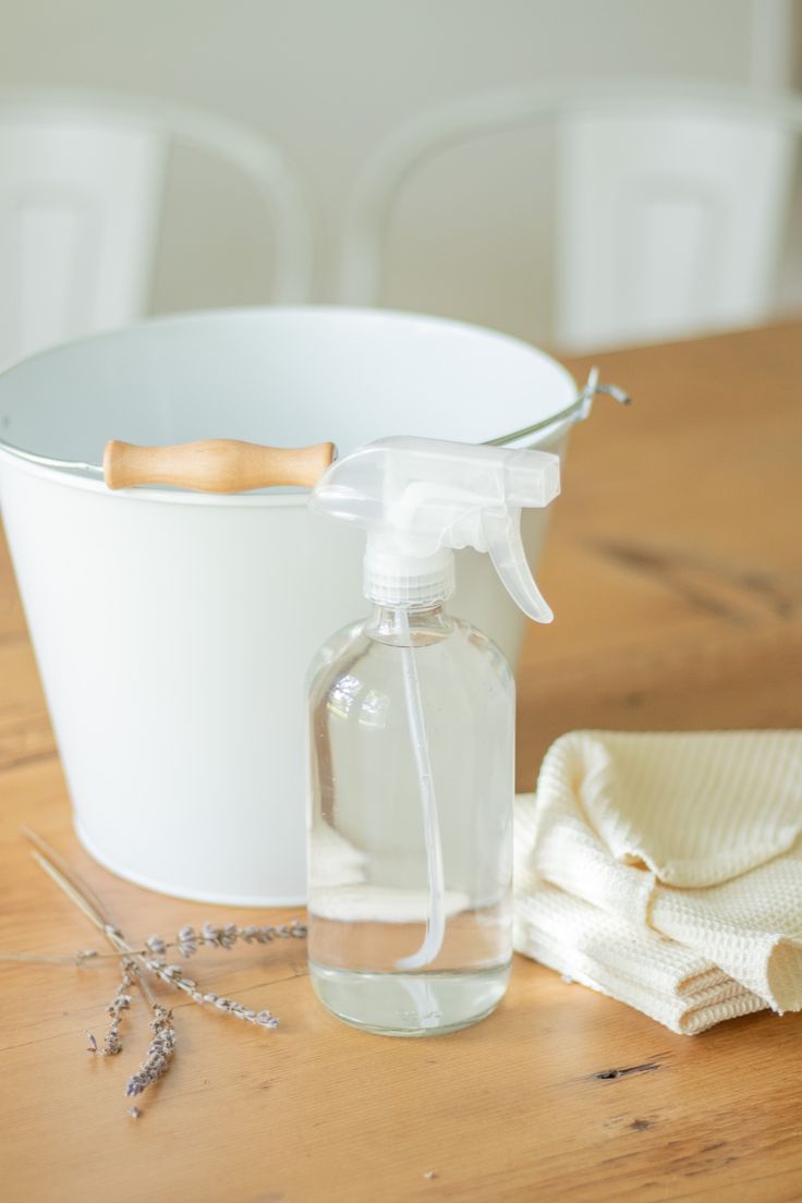 a white bucket and glass bottle on a wooden table