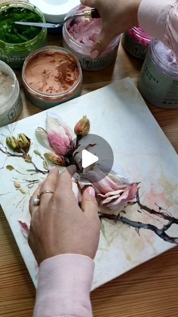 a person is painting flowers on a piece of paper