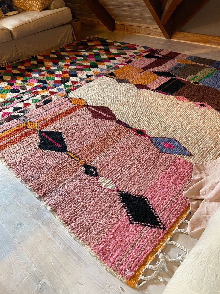 a multicolored area rug on the floor in a living room with a couch