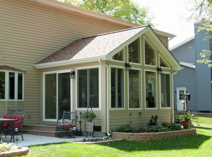 a house that is sitting in the grass next to a lawn with chairs on it