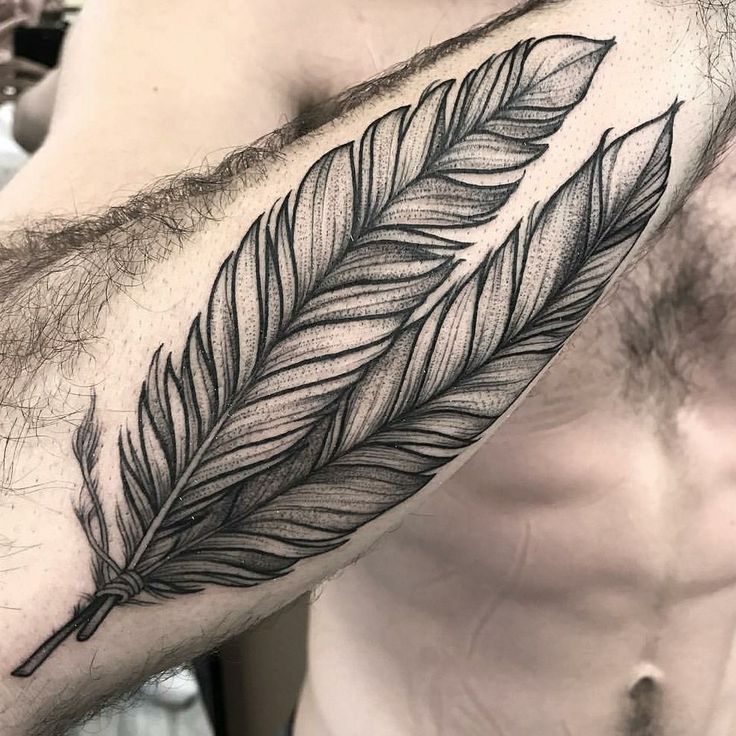 a man's arm with a feather tattoo on it