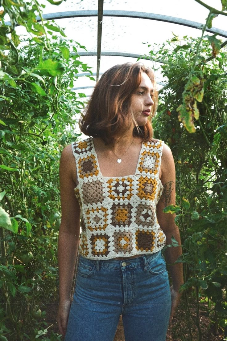 a woman is standing in the middle of some plants and looking off into the distance