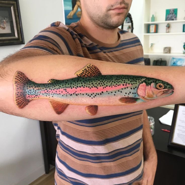 a man with a colorful fish tattoo on his arm