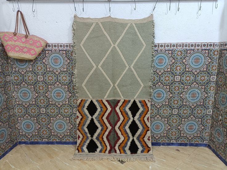 a room with several rugs on the wall and a purse hanging up against the wall