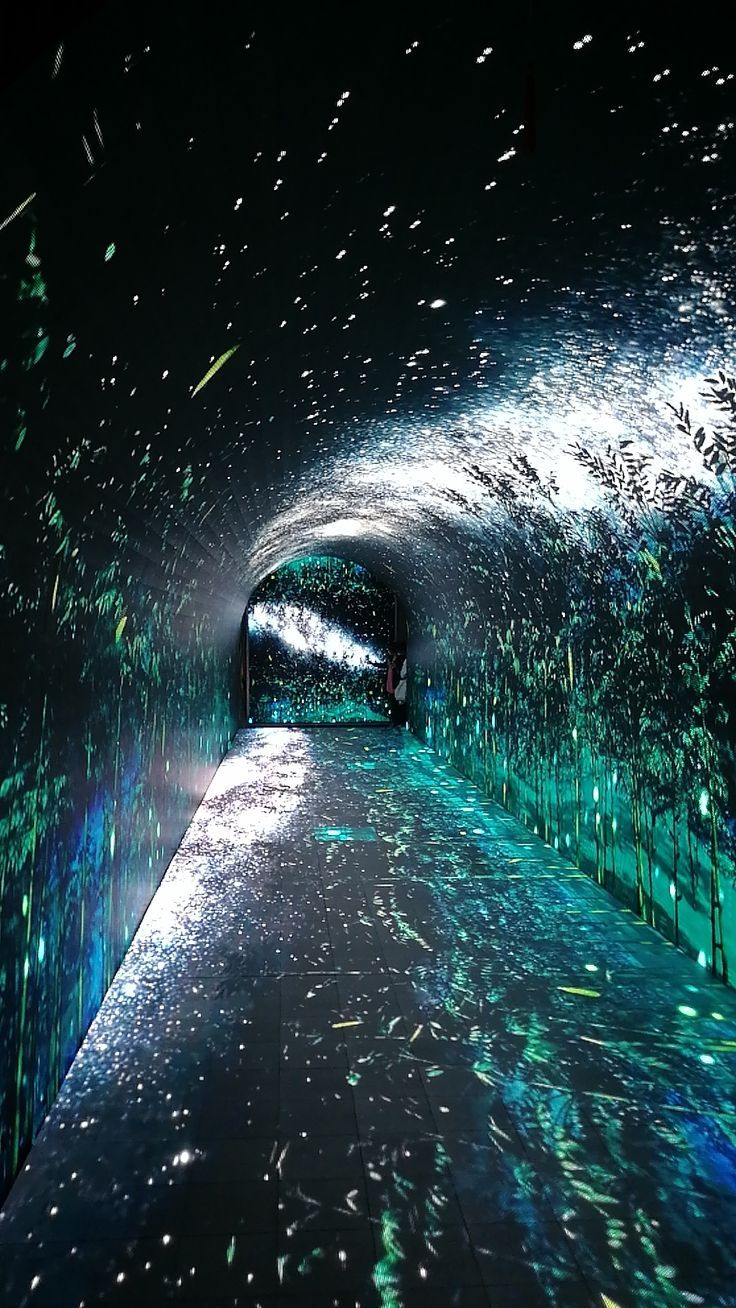 a tunnel that is lit up with green and blue lights in the dark, filled with confetti sprinkles