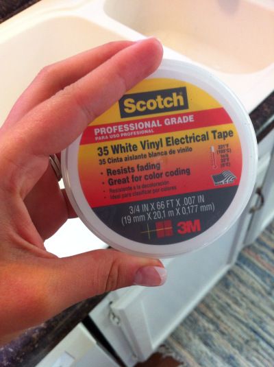 someone holding up a white vinyl electrical tape in front of a sink and counter top