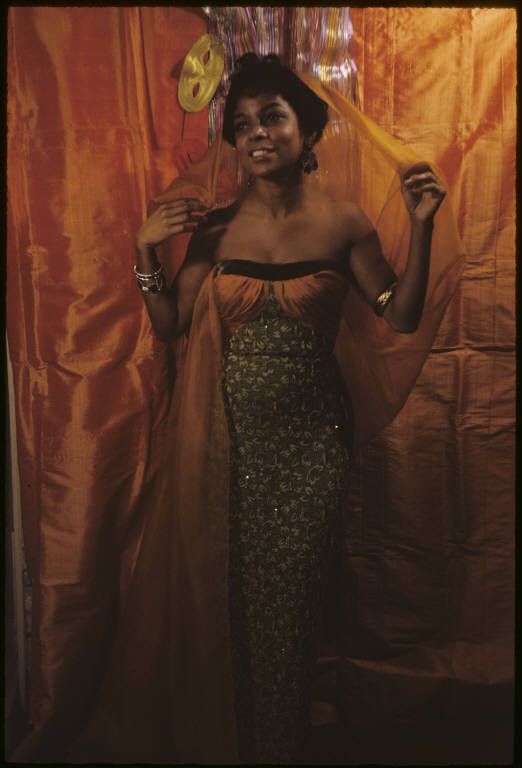 a woman in a dress and hat holding a fan