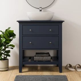 a white sink sitting on top of a blue dresser next to a potted plant