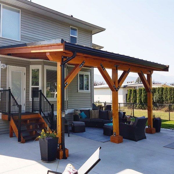 a covered patio with couches and chairs in front of a house on a sunny day