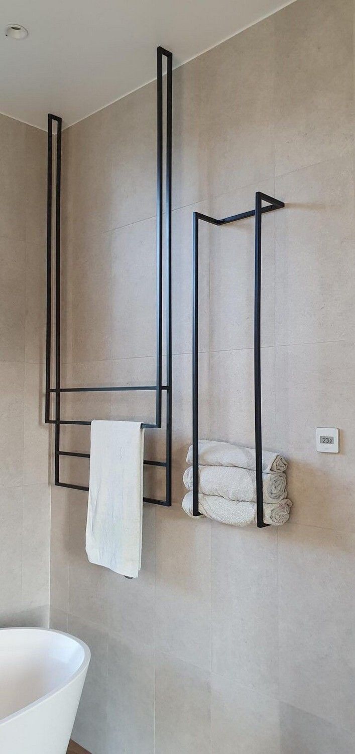 a white bath tub sitting next to a wall mounted towel rack