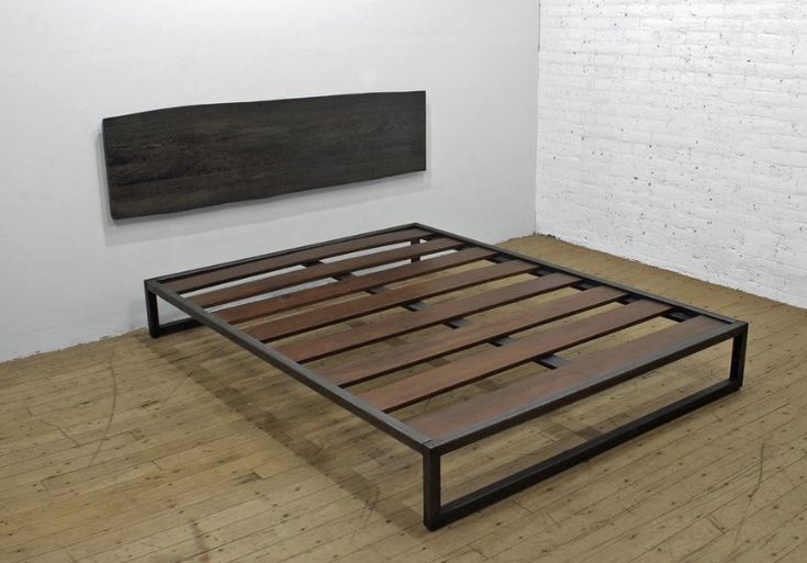 a bed frame sitting on top of a hard wood floor next to a white brick wall