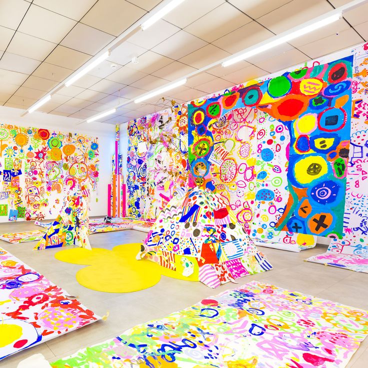 an art gallery with brightly colored paintings and rugs on the floor in front of it