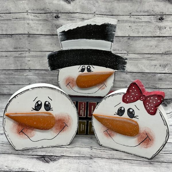 three snowmen with hats and bows on their heads