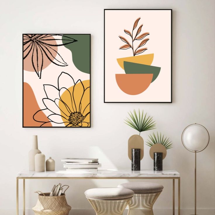 two framed art prints hanging on the wall above a table with chairs and vases