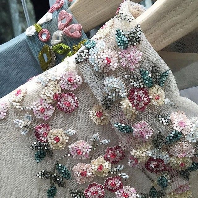 a close up of a piece of cloth with beading on it and flowers in the middle