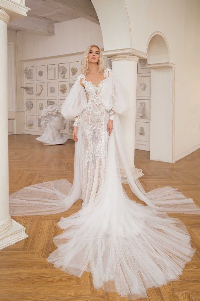 a woman in a white wedding dress standing on a wooden floor with long veils