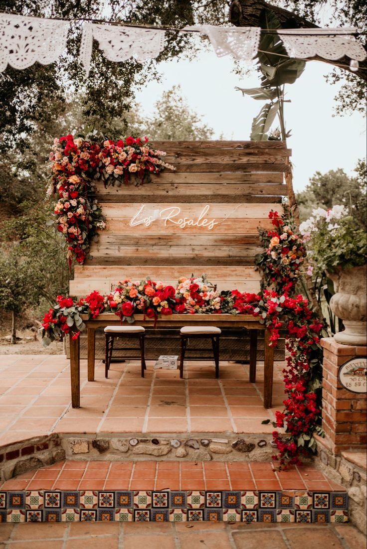 a wooden bench covered in flowers and greenery