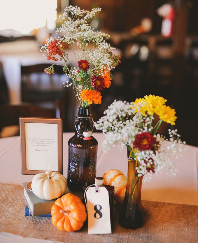 a table topped with vases filled with flowers and pumpkins