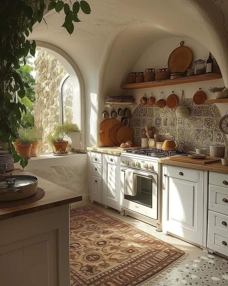 a kitchen with an arched window and potted plants on the counter top in front of it