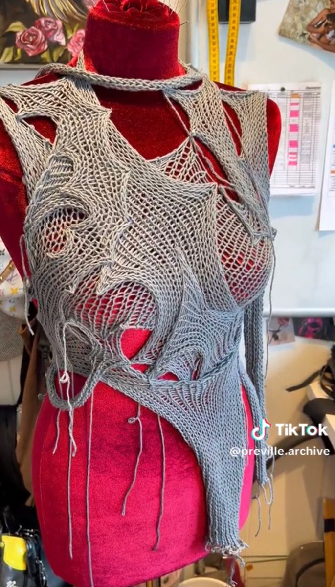 a mannequin is covered in silver thread and red fabric, with an intricate design on the back