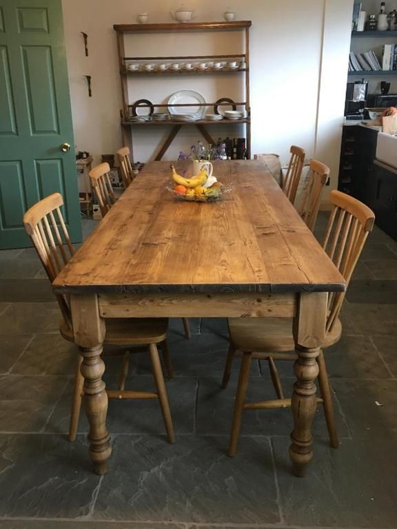 a wooden table with chairs around it in a kitchen next to a green door and shelves