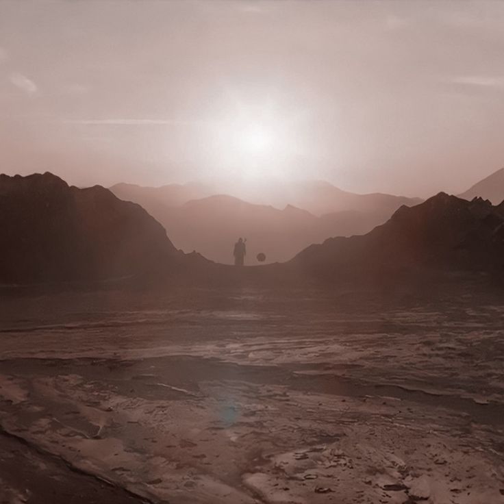 a person standing in the middle of a barren area with mountains and hills behind them