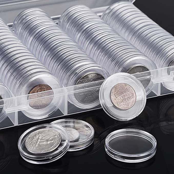 an assortment of coins in a clear plastic container on a black surface with the lid open