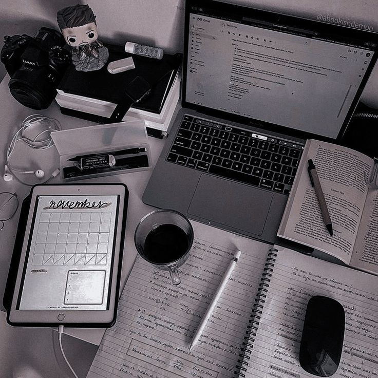 an open notebook sitting on top of a desk next to a laptop computer