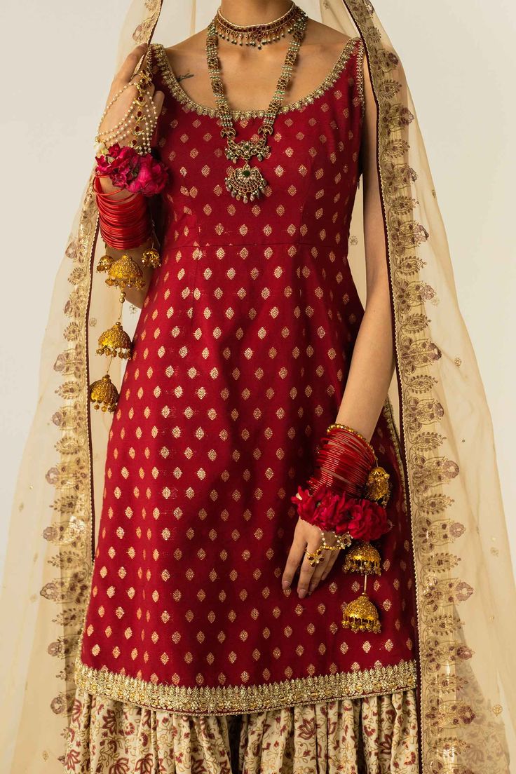 PRODUCT DESCRIPTION: Top: Zari JacquardBottom: Raw SilkDupatta: Organza This block-printed gharara with gota finishings is paired with a deep red sleeveless shirt, embellished with zardozi work on the hemline and sides. Banarasi Silk Sets With Gota Work For Reception, Semi-stitched Brocade Sharara With Gota Work, Traditional Brocade Palazzo Set With Zari Work, Banarasi Silk Sharara For Reception In Transitional Season, Transitional Reception Banarasi Silk Sharara, Traditional Palazzo Set For Reception With Dabka Detailing, Wedding Banarasi Silk Palazzo Set For Navratri, Traditional Banarasi Silk Sharara With Dabka, Brocade Sharara With Cutdana For Reception