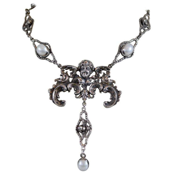 This one of a kind sterling silver drop necklace accentuates heavenly elements found throughout history in sacred adornments, sculpture and architecture. A grand figural angel establishes the bold center element for this necklace which has a winged cherub link lavalier drop with a 12 x 10 mm oval freshwater pearl. Jill's original cherubic links with filigree form unique chaining with intermittent 12 x 10 mm Freshwater pearl cabochons. We hope you will review our numerous pictures from every angle so you can see the fine detail and beauty of this wonderful original drop necklace. If you need additional pictures please let us know as we are always happy to provide them. • A finely-wrought sterling silver lavalier drop necklace • 19.5 in. figural cherub link chain • Five 12 x 10 mm freshwater Baroque Angel, Silver Drop Necklace, Gold Lariat Necklace, Freshwater Pearl Necklaces, Multi Strand Necklace, Lariat Necklace, Drop Necklace, Baroque Pearls, Natural Pearls