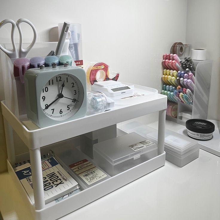 a white table topped with a clock and lots of crafting supplies on top of it